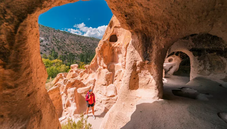 Woman in a red jacket looking at orange craters in a canyon