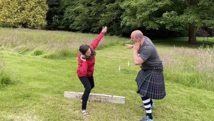 Man and woman posing to throw a steel ball in a large field