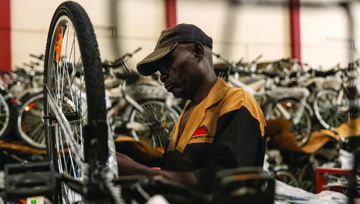 Man fixing a bike in a warehouse full of bicycles