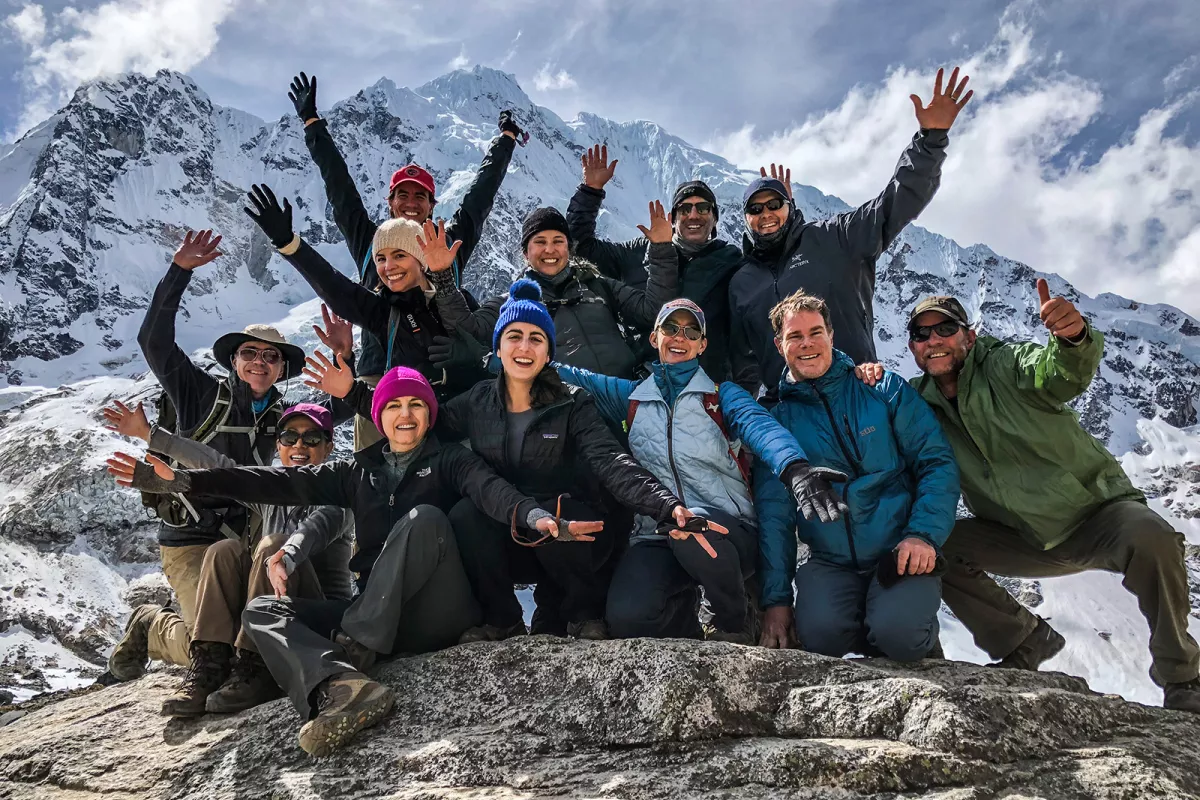 Group of guests on mountainside, all smiling, gesturing to camera.