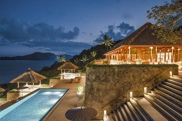 Hotel at night with lit up swimming pool