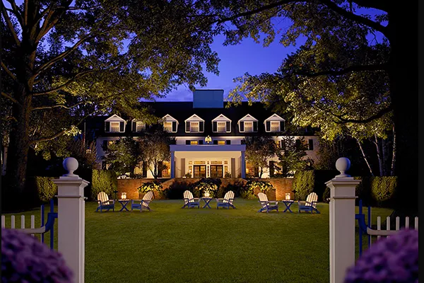 large house with Adirondack chairs in front lit up at night
