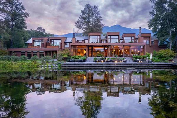 large hotel next to a lake and in front of a mountain