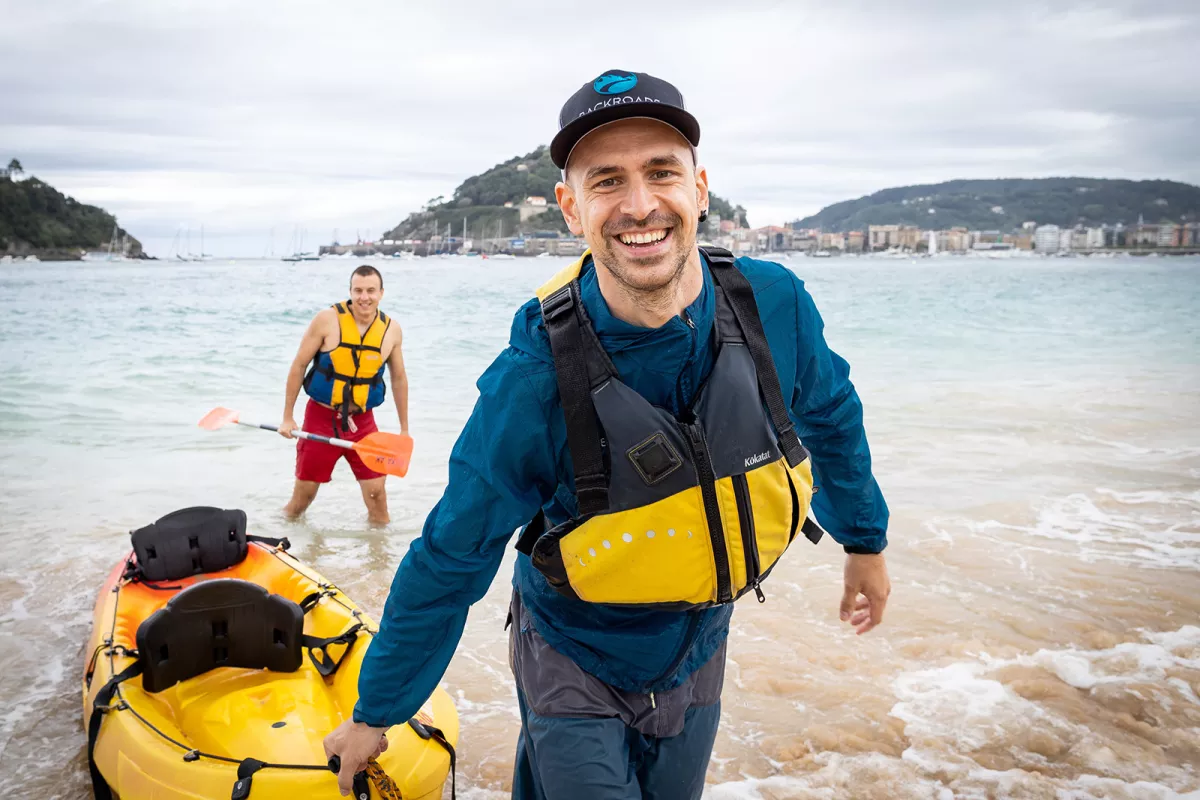 Man smiling while pulling a yellow raft from the ocean
