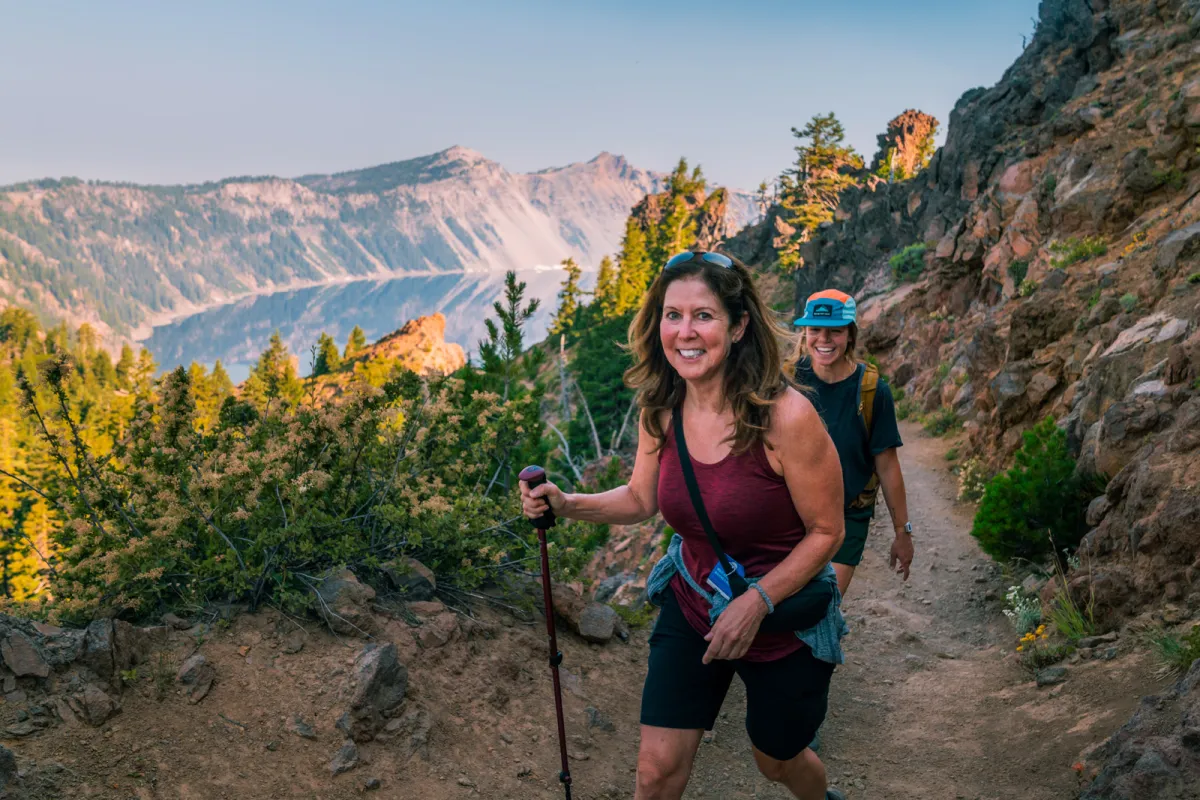 Two women smiling while ascending a dirt trail