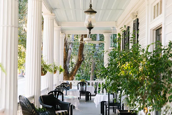 dining tables out on a covered porch with large white columns