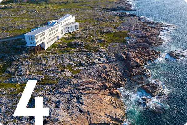 text:4; image: a white building stands on a rocky shoreline
