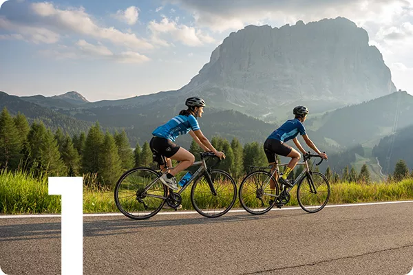 text:1; image: Two bikers cycle down a road