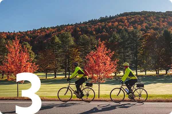 text:3; image: Two cyclists biking on a road with trees in the background