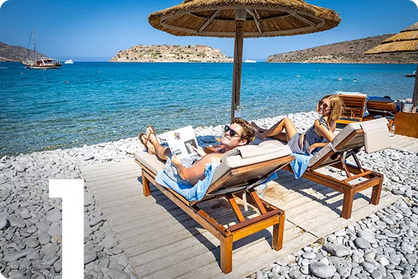 text:1; image: two people lying on lounge chairs on the beach