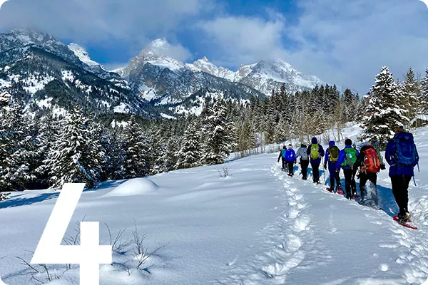 text:4; image: People hiking through a snowy field with mountains in the background