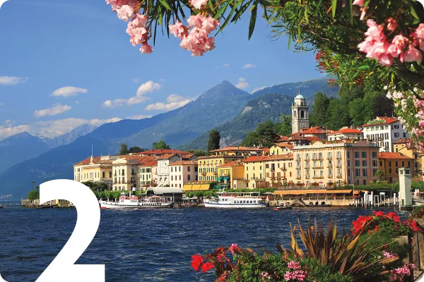 text: 2; image: Lake with buildings in the background and flowers in the foreground