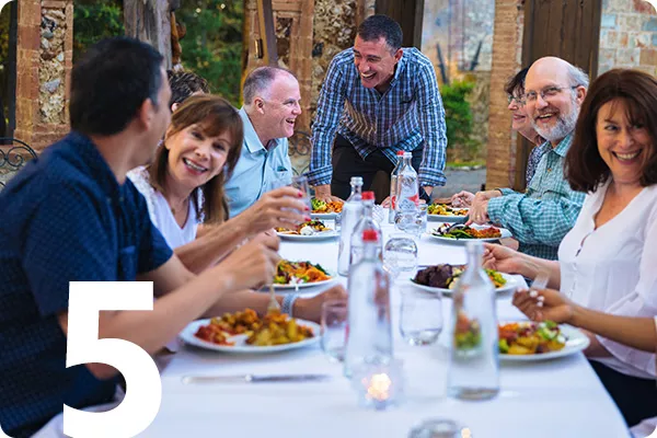 White number 5 overlayed over a group of travelers dining al fresco 