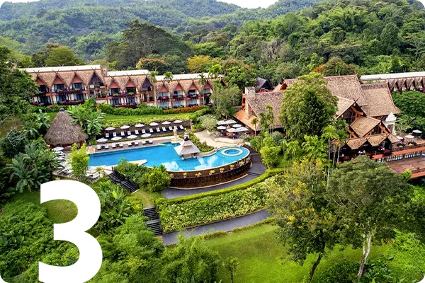 text:3; image: Aerial shot of a hotel and pool surrounded by greenery