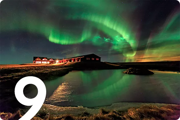 text:9; image: northern lights shining  green over a large building