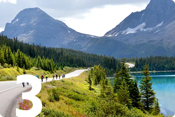 text:3; image: people biking down a tree lined path towards a mountain