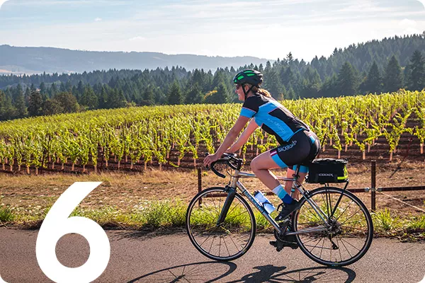A man bikes by a vineyard
