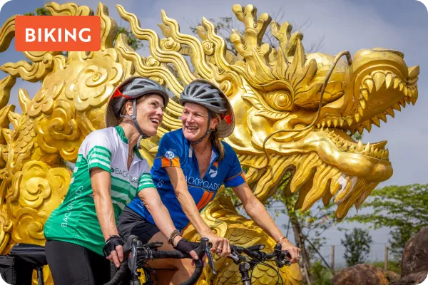 Two cyclist ride by yellow dragon
