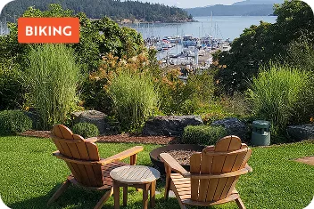 Two wooden lawn chairs on top of a hill, looking towards a large lake