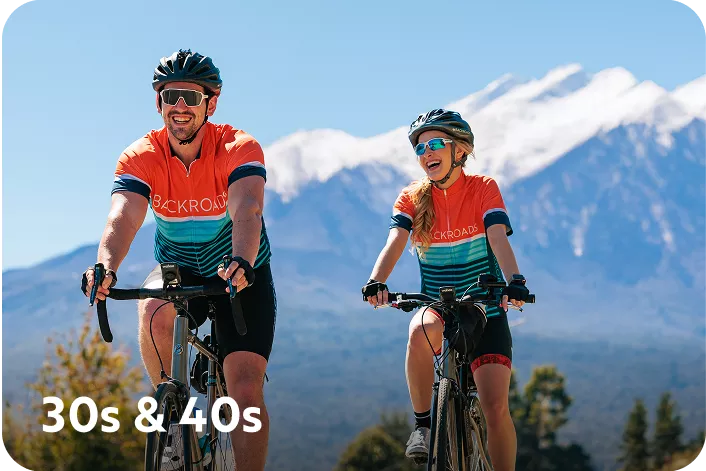Man and woman wearing biking gear, while smiling and biking