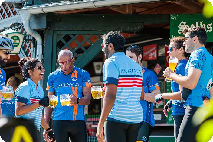 Group of bikers in a circle, laughing while holding up alcoholic drinks