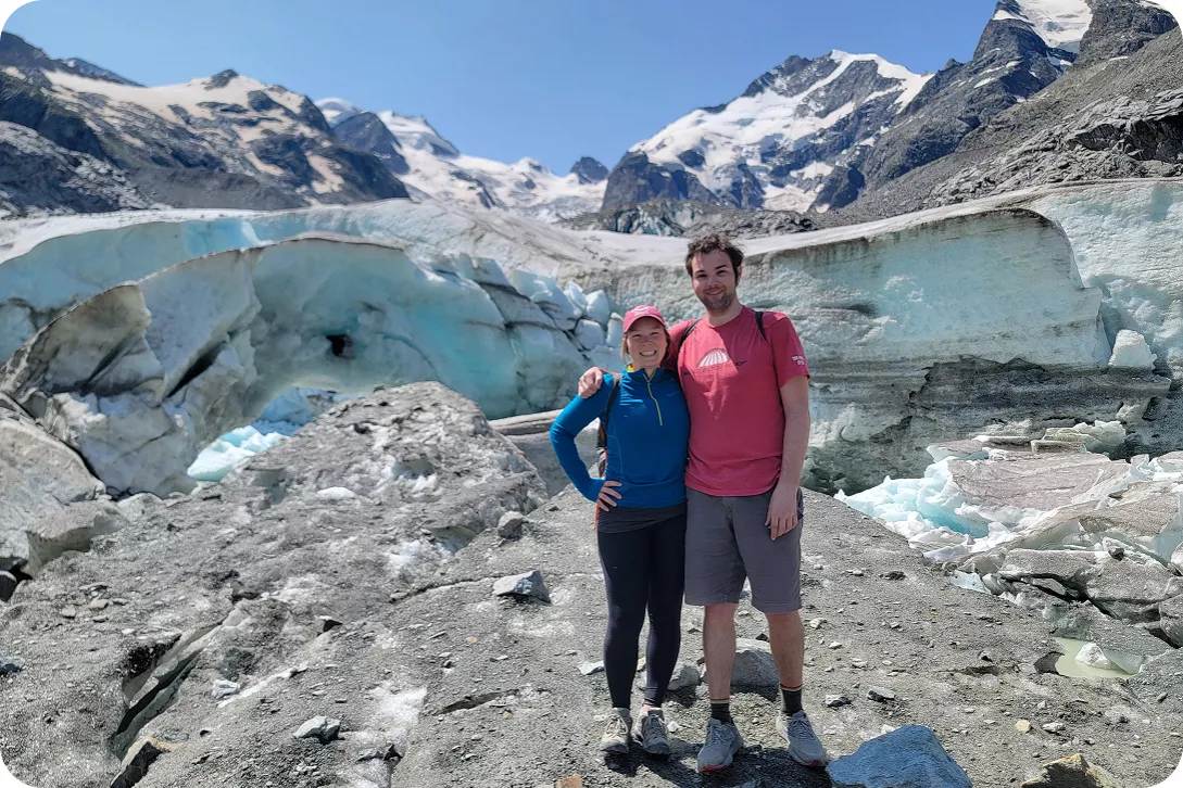 Two employees pose on their backroads trip in front of a mountain