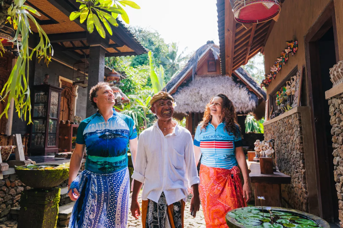 Two men and one woman smiling while walking through an alleyway of houses