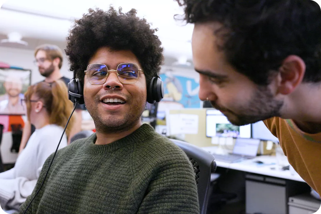 Two men smiling while looking at a computer screen