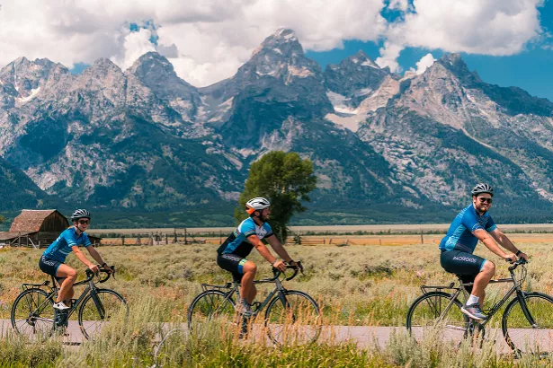 Group of people biking on a road with an empty valley and large mountains in the distance