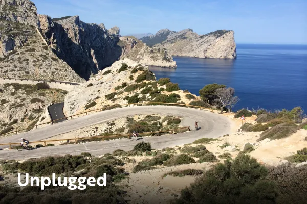 Winding road with biker, Unplugged is written over top of the image.