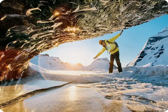 Person smiling in front of a cave, with a glacier in the background