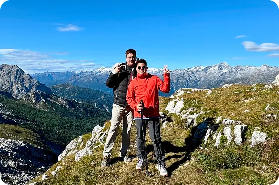 Two men on top of a cliff, smiling while wearing sunglasses