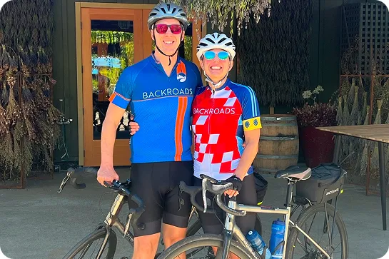 Man and woman wearing bike jerseys and standing in front of two bicycles