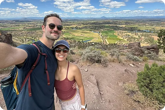 Man and woman wearing sunglasses, with a large valley behind them