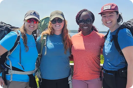 Group of 4 women smiling with arms around their shoulders