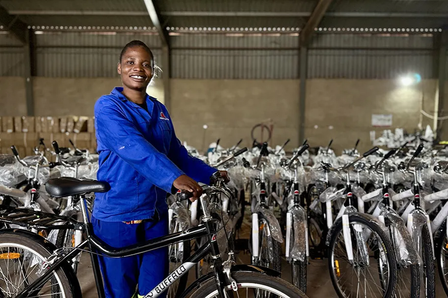 Women in a blue jacket holding a bicycle, in a warehouse full of bicycles
