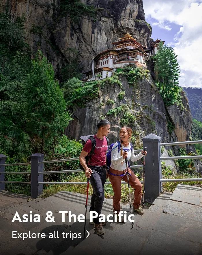Man and woman walking up stairs, with a large temple on a cliff
