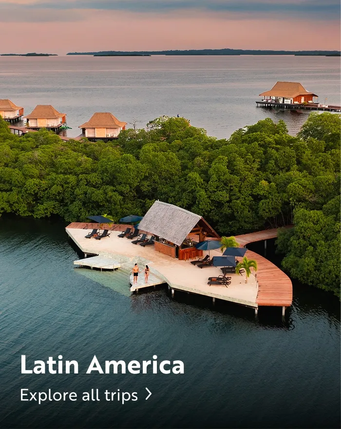 Two people standing on a balcony by the water