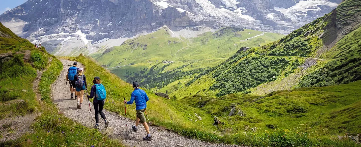 Group of people hiking on a trail with large mountains in the distance