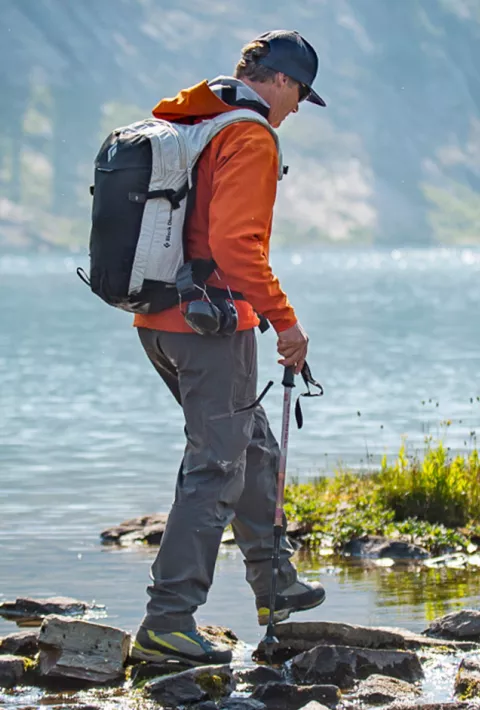 Child and adult crossing stream while hiking