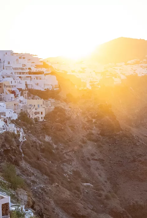 white houses built into a mountainside overlooking water