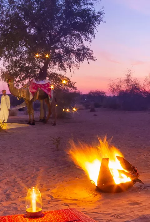 low tables with red tablecloths set up on the beach during sunset