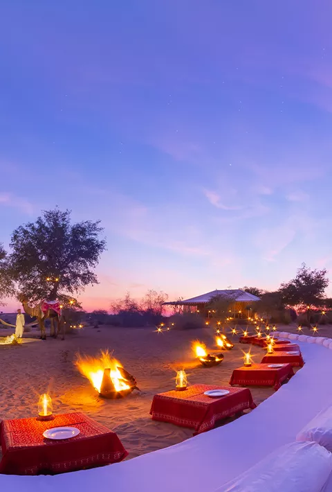 low tables with red tablecloths set up on the beach during sunset