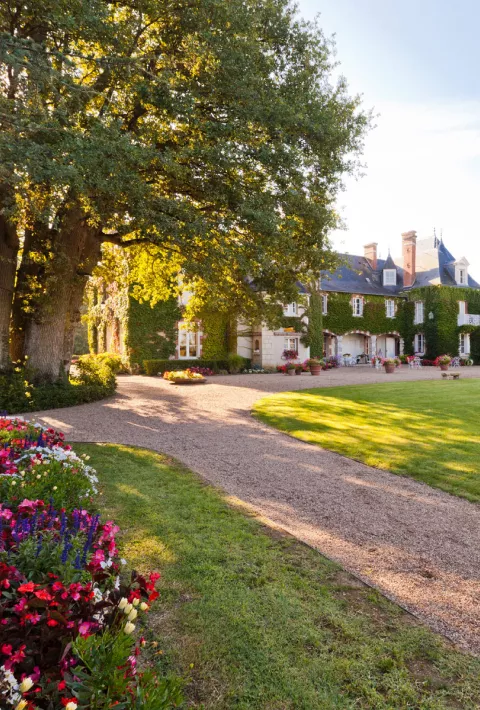 Exterior view of large, white building with large lawn and dirt trail in front