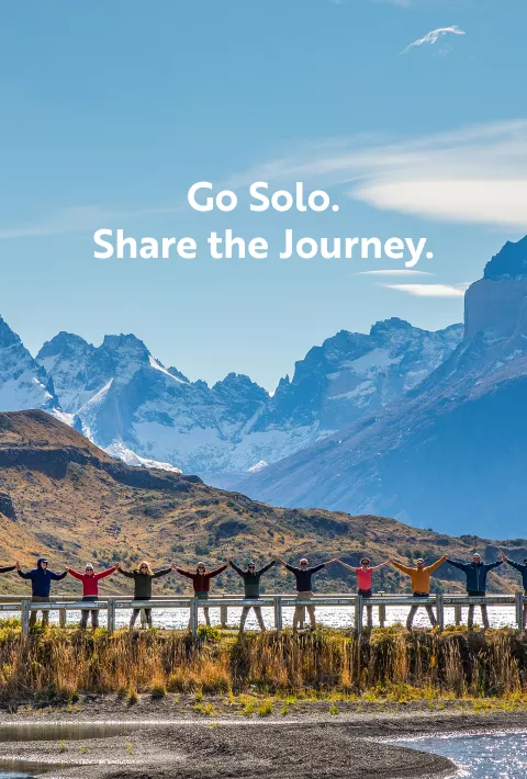 People standing arm to arm in front of a mountain range