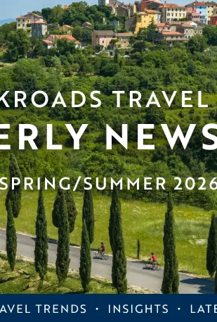 The Backroads Travel Advisor Quarterly Newsletter Spring/Summer 2026 is written over rolling hills with small multicolored homes and tree lined roads.