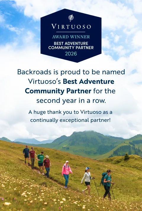 Backroads is proud to be a Virtuoso's Best Adventure Community Partner for the second year in a row, a huge thank you to Virtuoso as a continually exceptional partner is written over a hilly mountain side with 7 hikers walking down a trail.