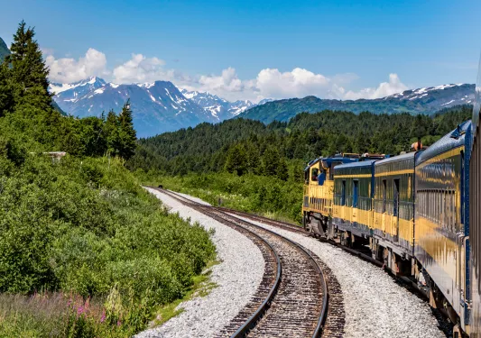 Yellow train with mountains in the background in Alaska
