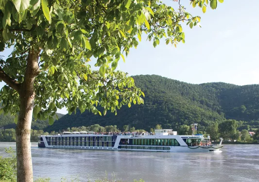 POV shot of AMA ship from riverside, floating down river.