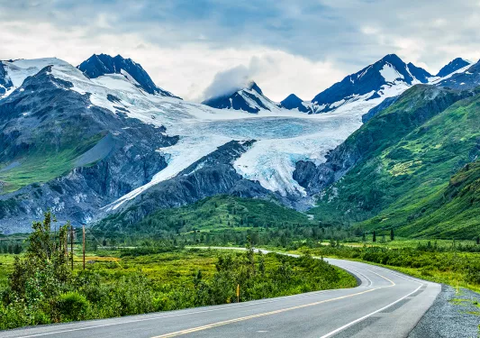 Winding road leading to snow covered mountains in Alaska